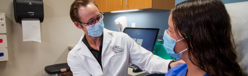 Dr. Jared Rickert examining a patients shoulder.